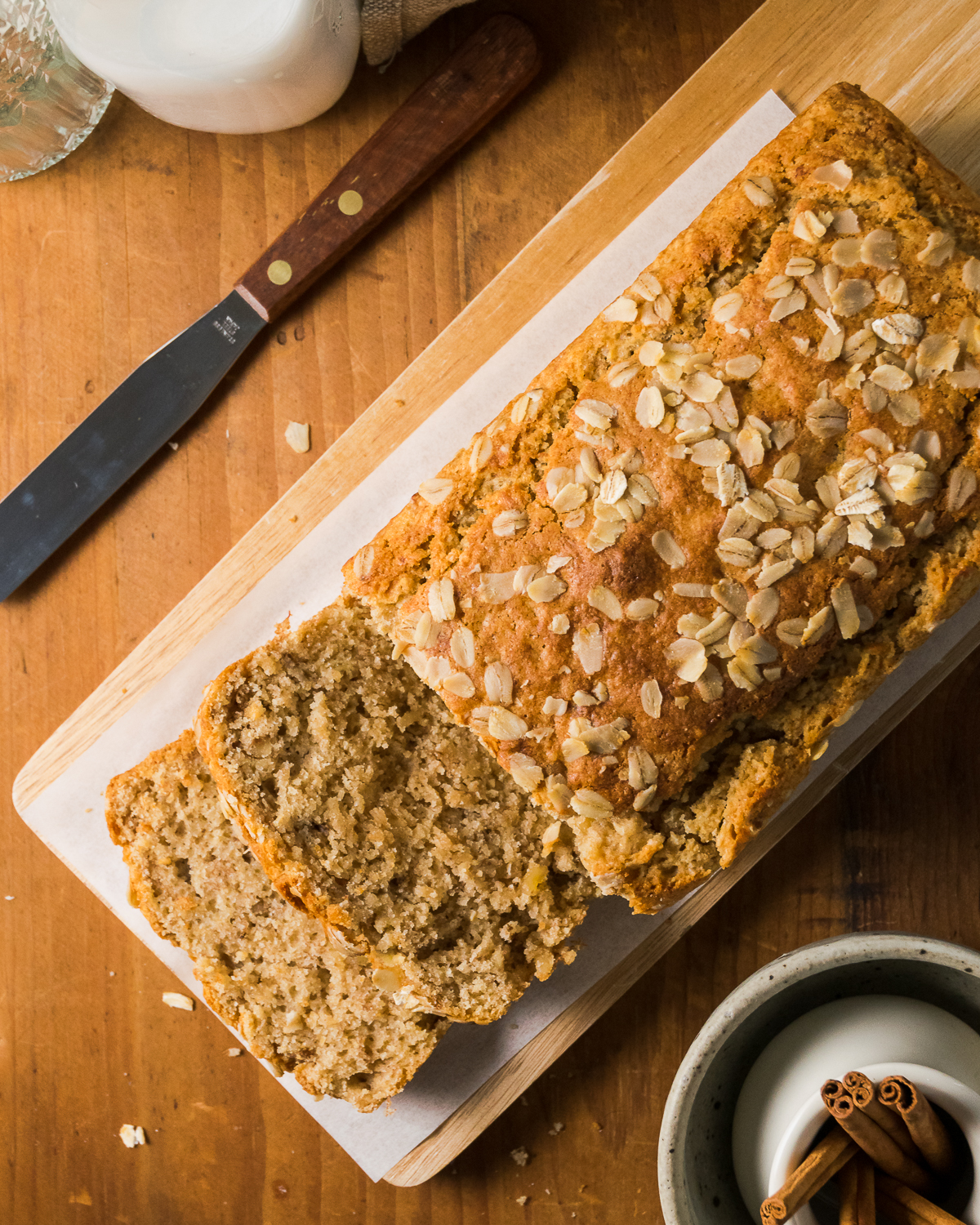 A loaf of maple banana bread sliced and sitting on a cutting board.