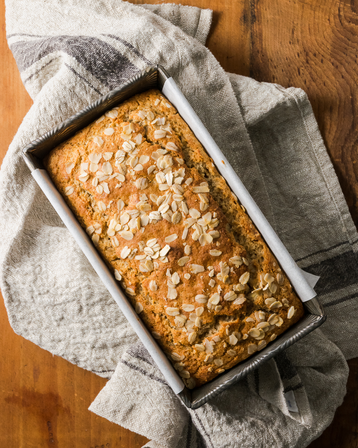 A loaf of freshly baked maple banana bread in a metal baking tin.