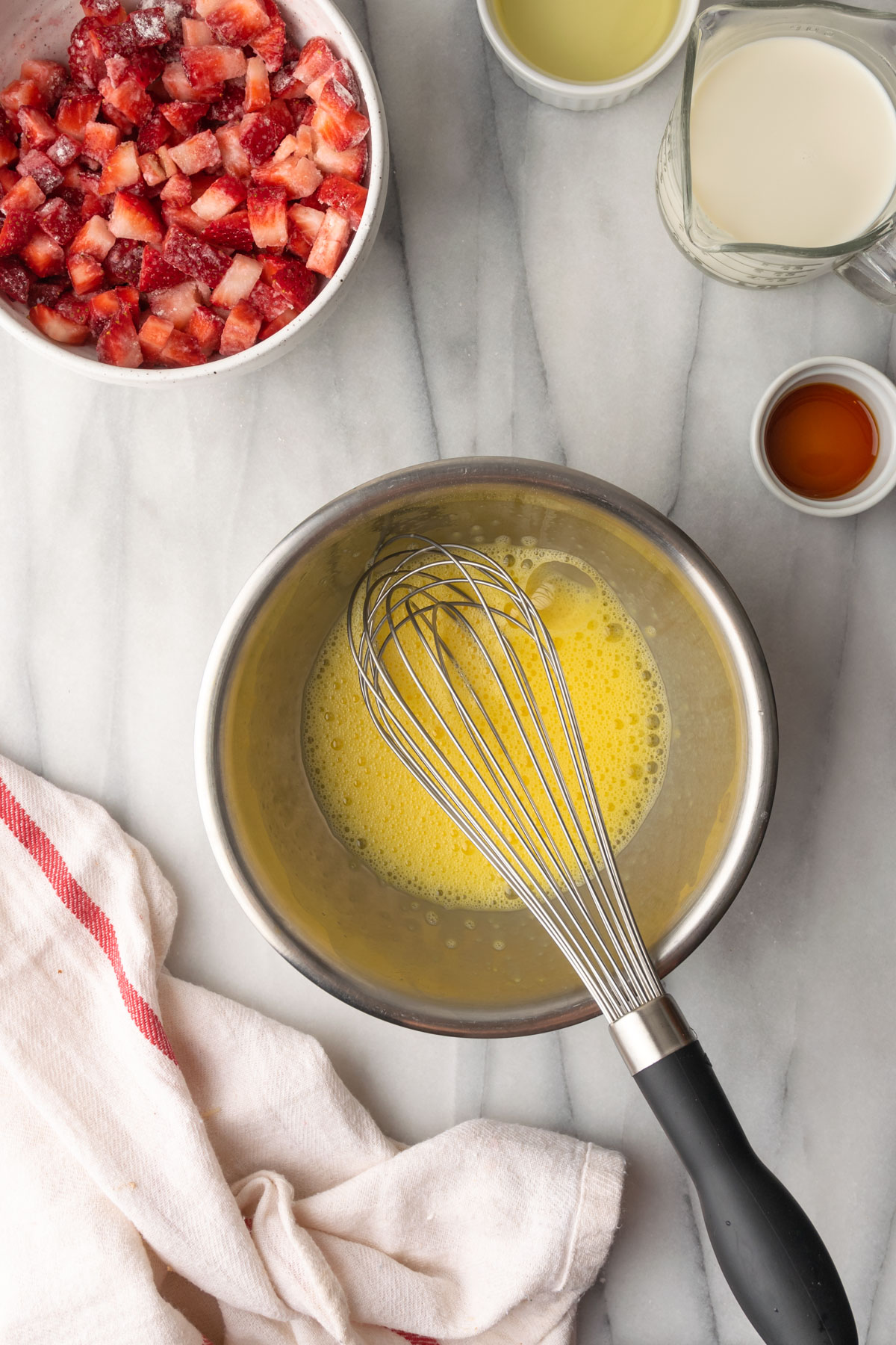 Whisked eggs in a small metal mixing bowl.