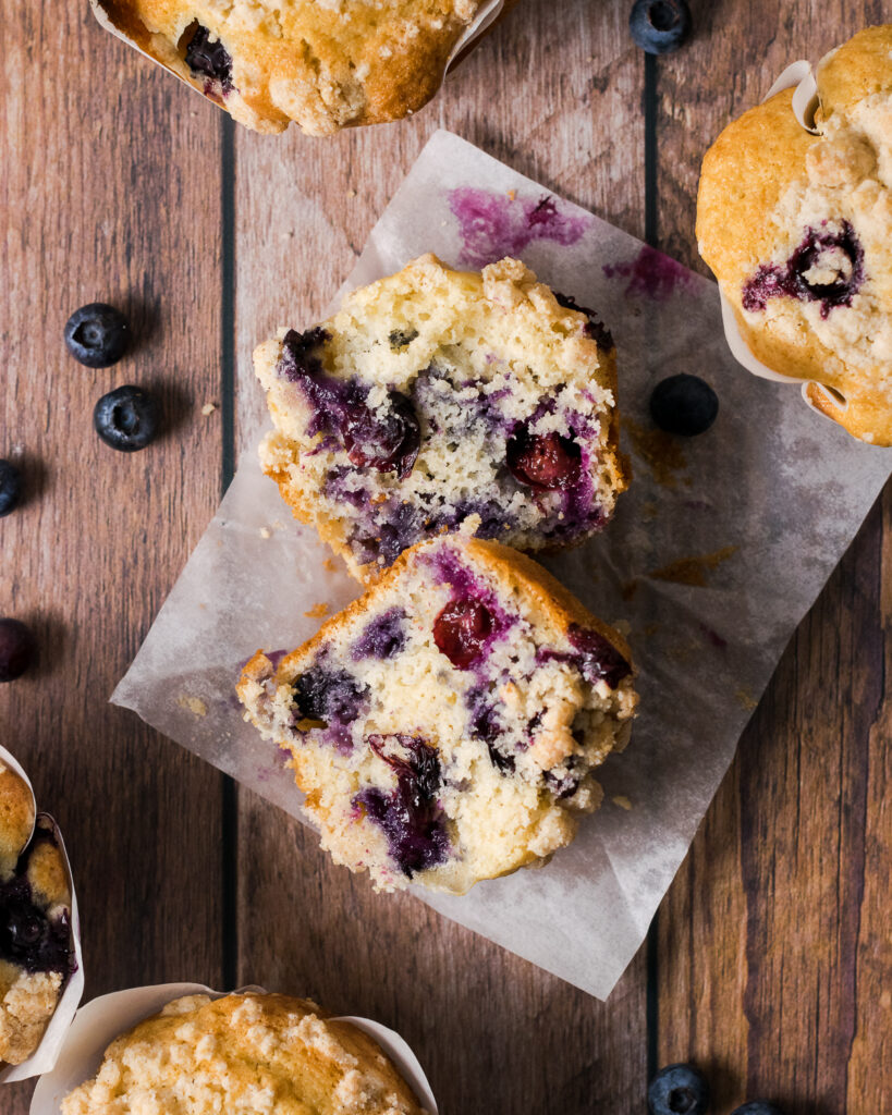 A cut open blueberry muffins on a piece of parchment paper. 