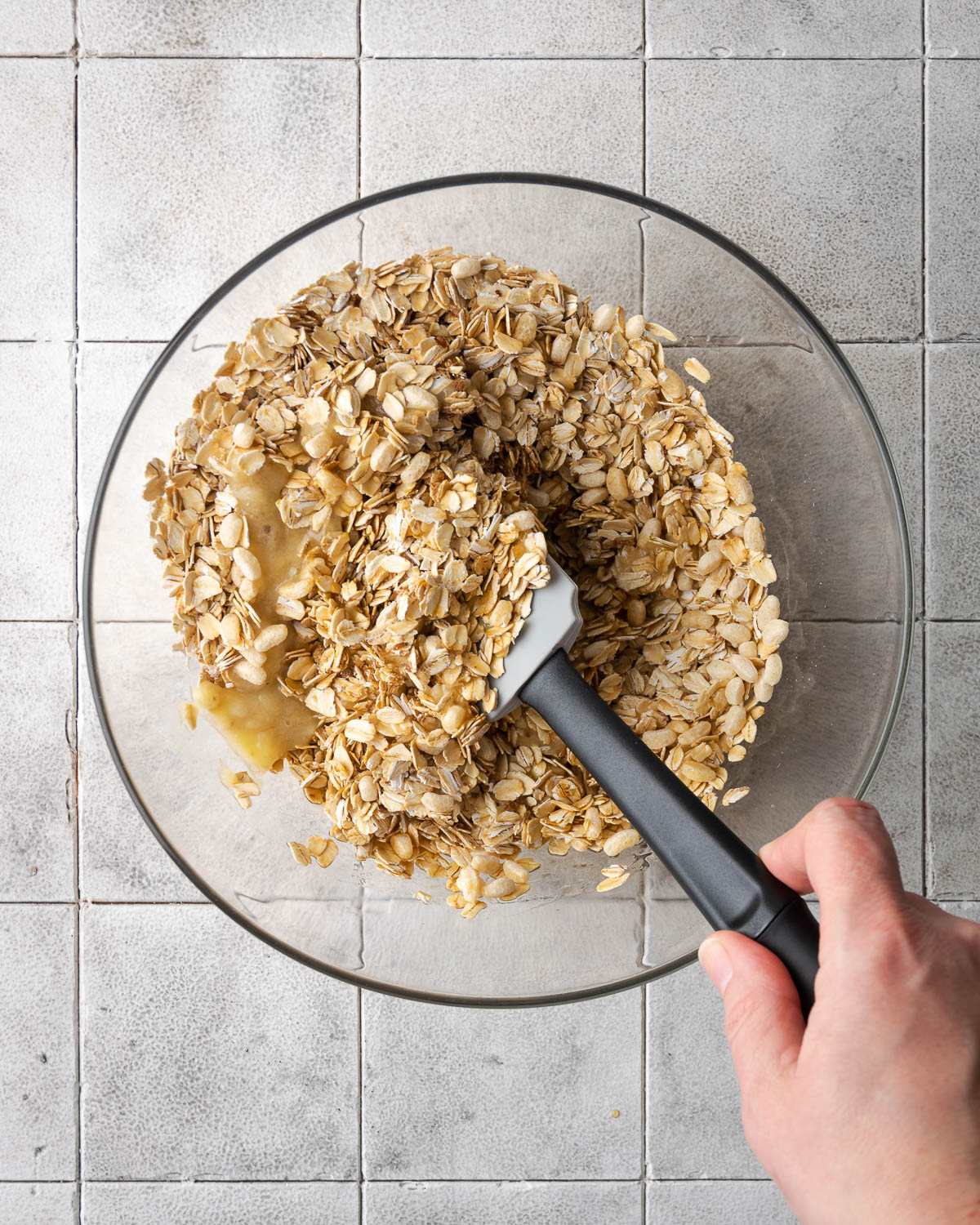 Granola being mixed together with a rubber spatula.