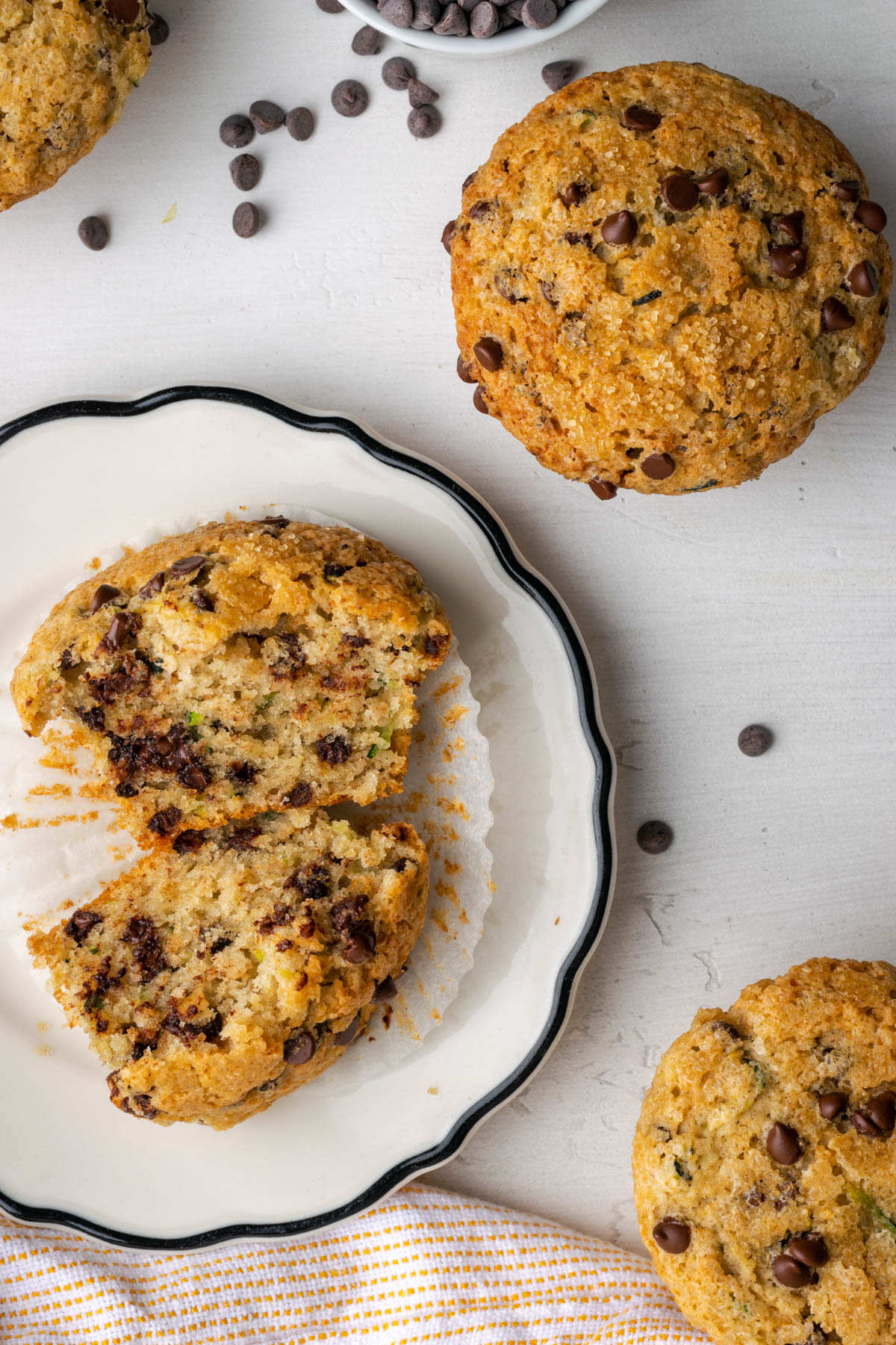 Sliced open zucchini chocolate chip muffins on a white table.