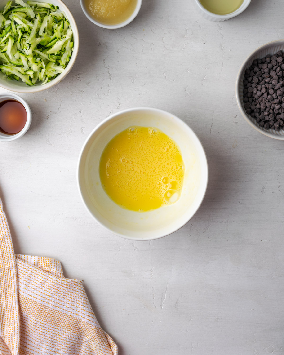 An egg whisked to frothy bubbles in a small white bowl.