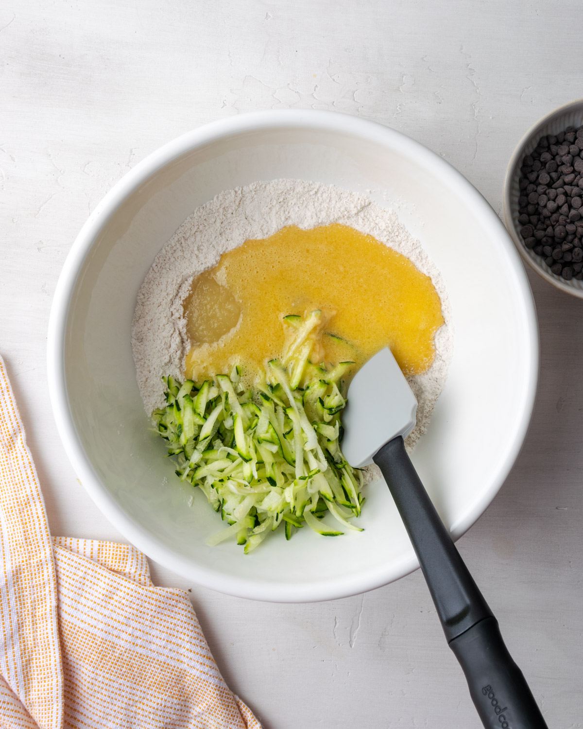 Egg, applesauce and shredded zucchini being added to the bowl of dry ingredients.