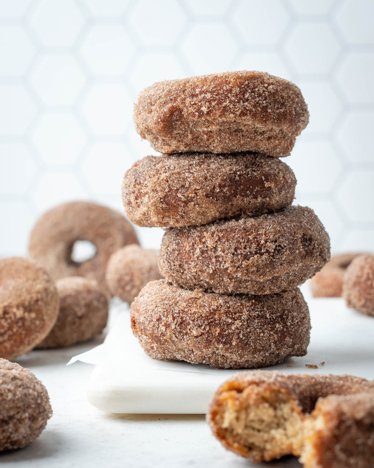 A stack of gluten free apple cider donuts on a white cutting board.