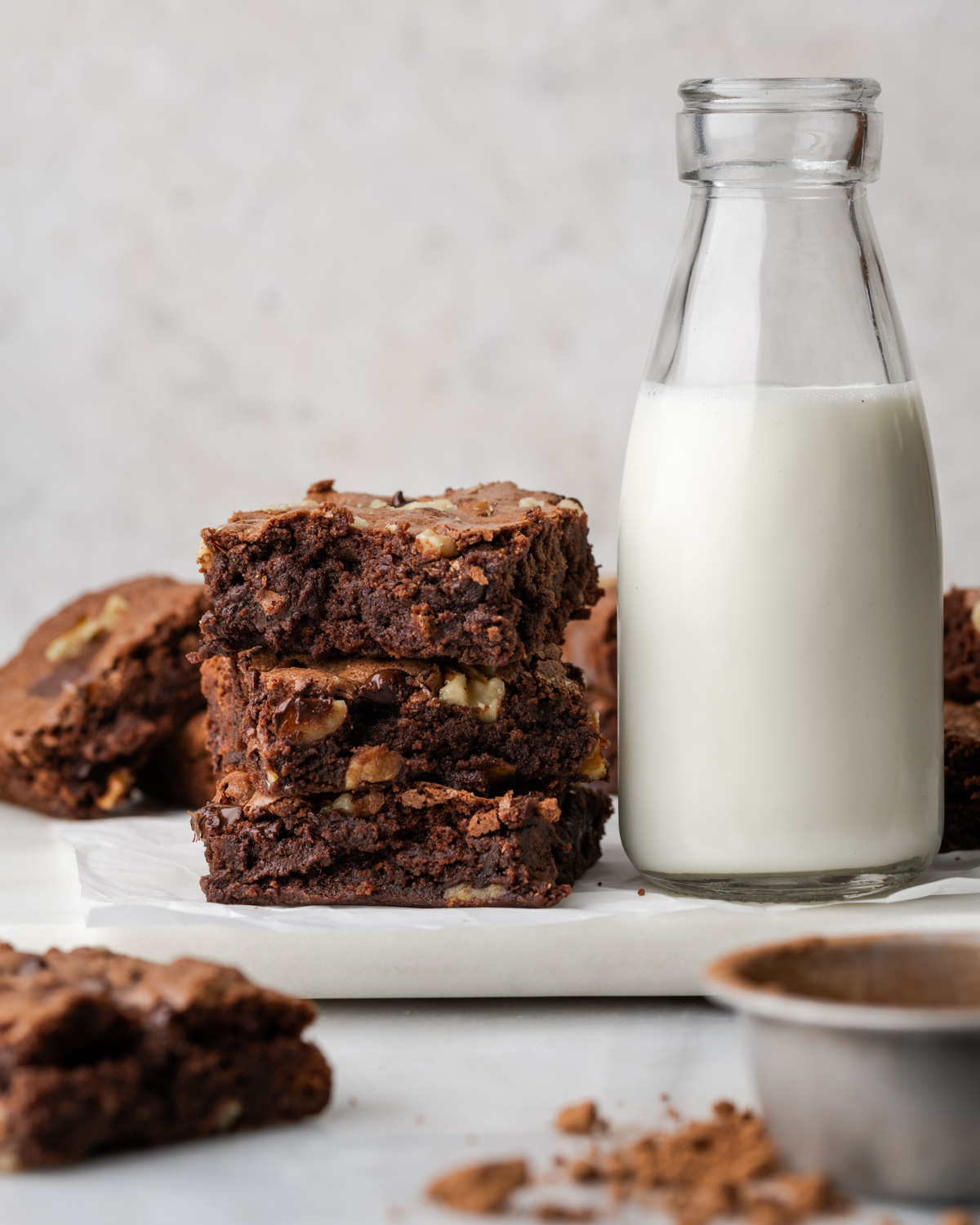 A stack of brownies next to a jar of milk.