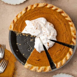 A gluten free pumpkin pie cut into slices and topped with whipped cream.