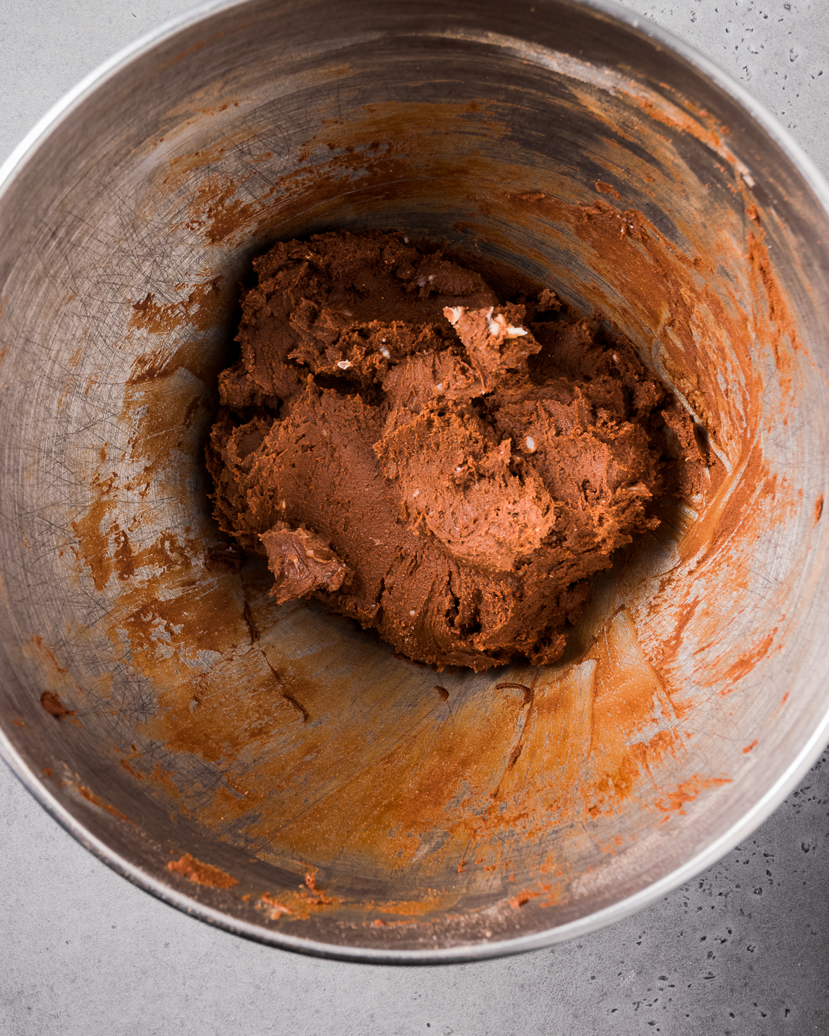 Chocolate cookie dough in a large metal mixing bowl.