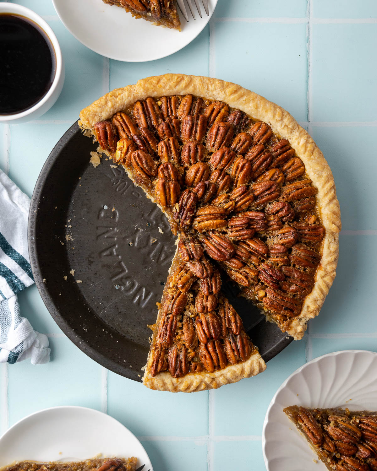 A sliced pecan pie on a light blue table.