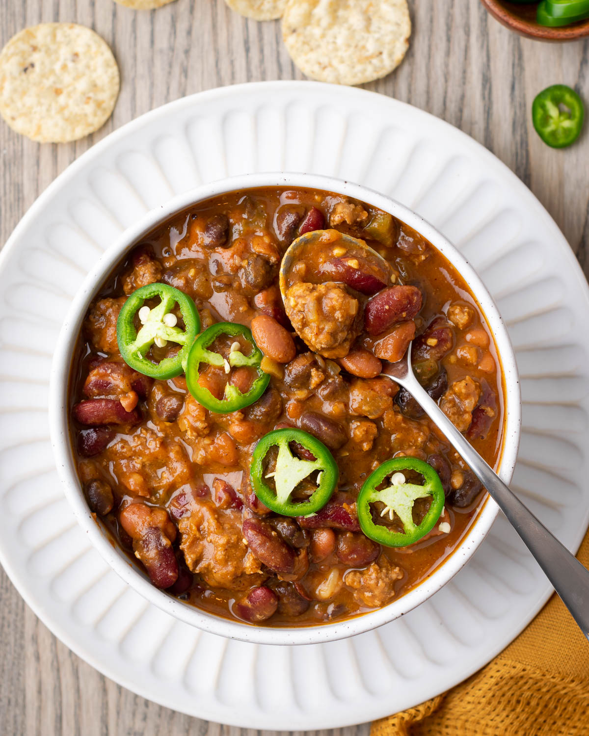 A bowl of pumpkin chili topped with sliced jalapenos.