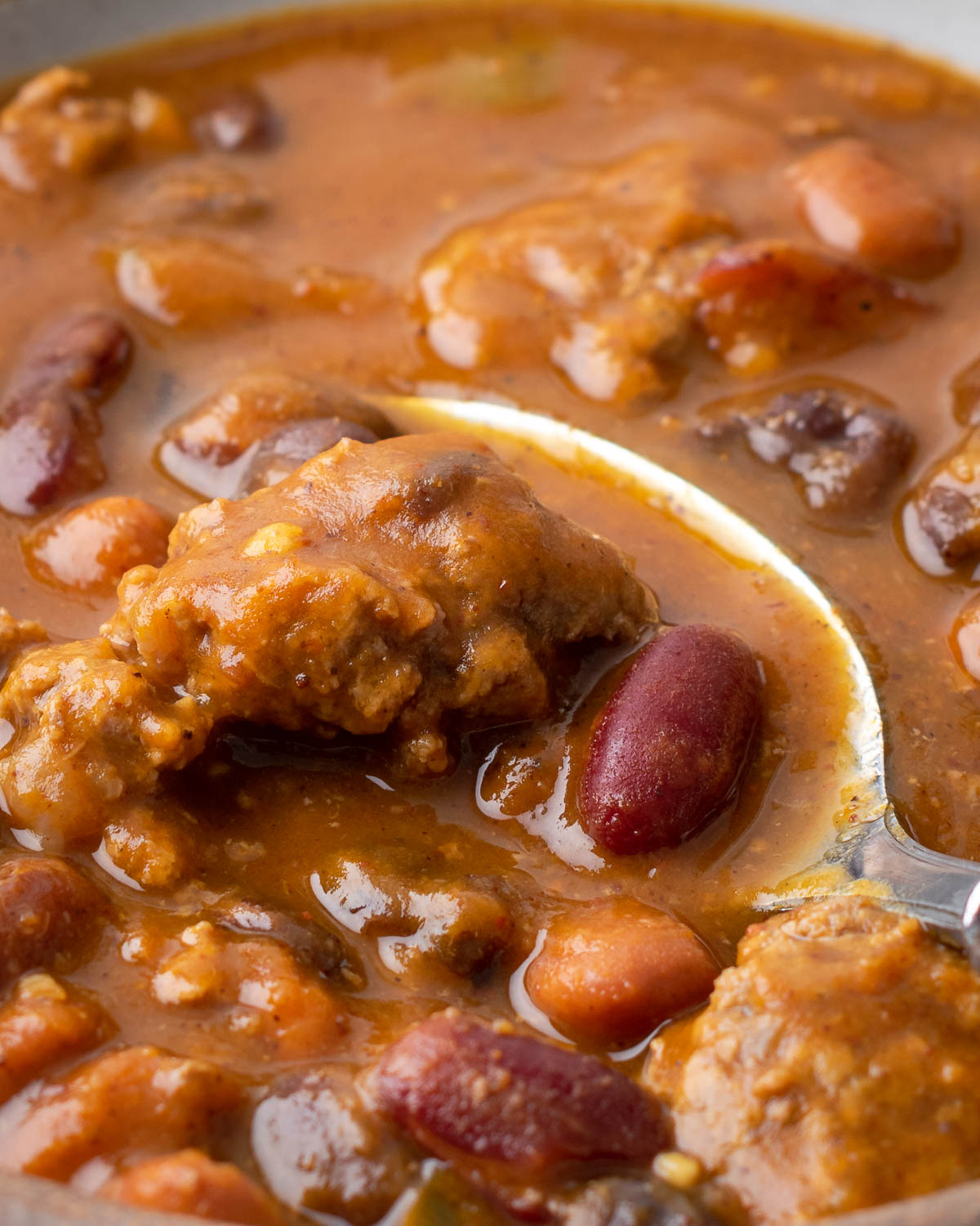 Beef mixed into chili in soup pot.