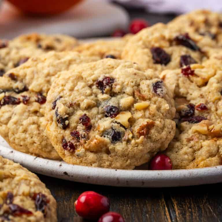 A batch of gluten free cranberry orange oatmeal cookies on a ceramic plate.