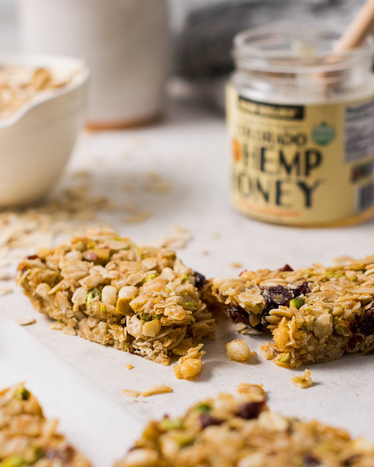 A broken granola bar sitting next to a jar of honey.