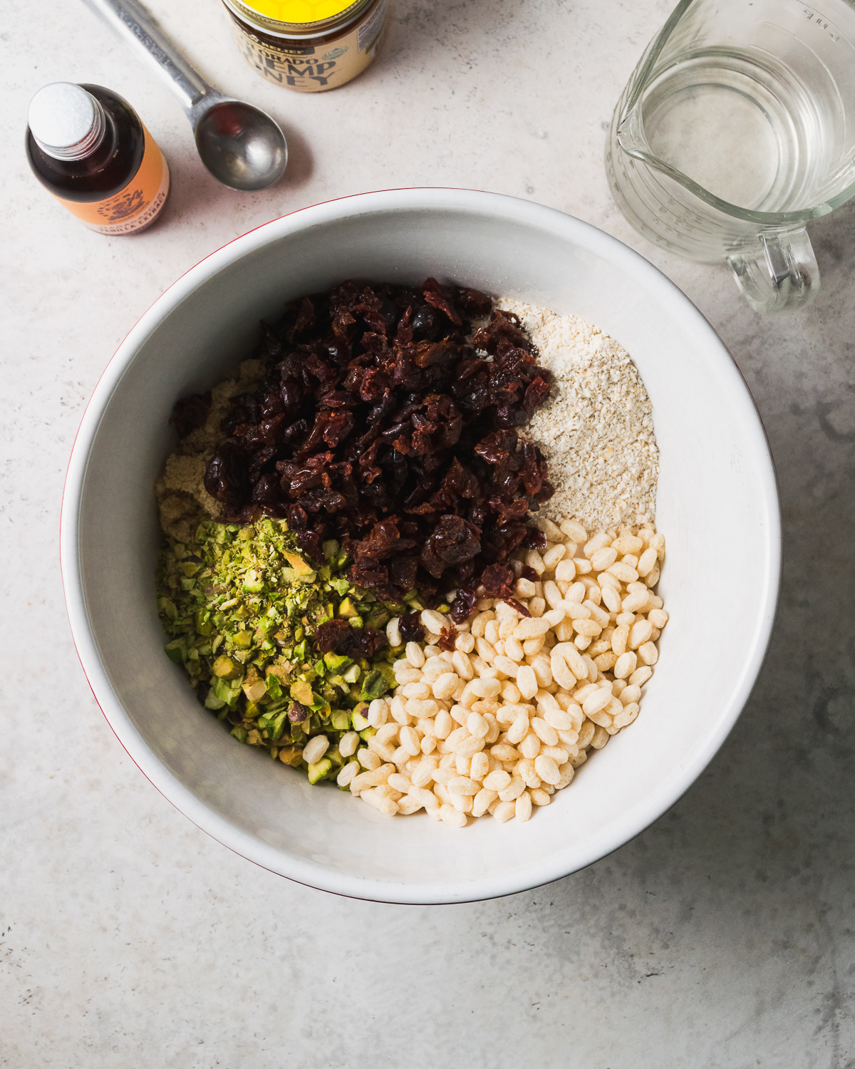 Oats, puffed cereal, dried fruit and nuts combined together in a large white mixing bowl.