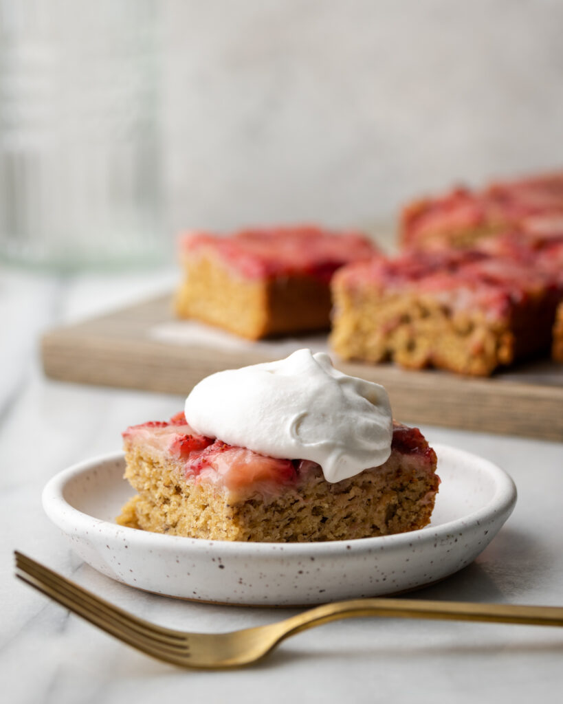 A slice of upside down cake topped with whipped cream.