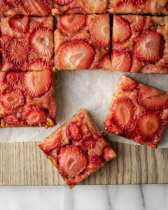 Squares of strawberry upside down cake on cutting board.
