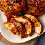 A sliced chicken breast drizzled with spicy honey sauce on a serving tray.