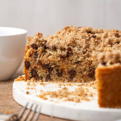 A sliced chocolate chip coffee cake sitting on a white serving dish.
