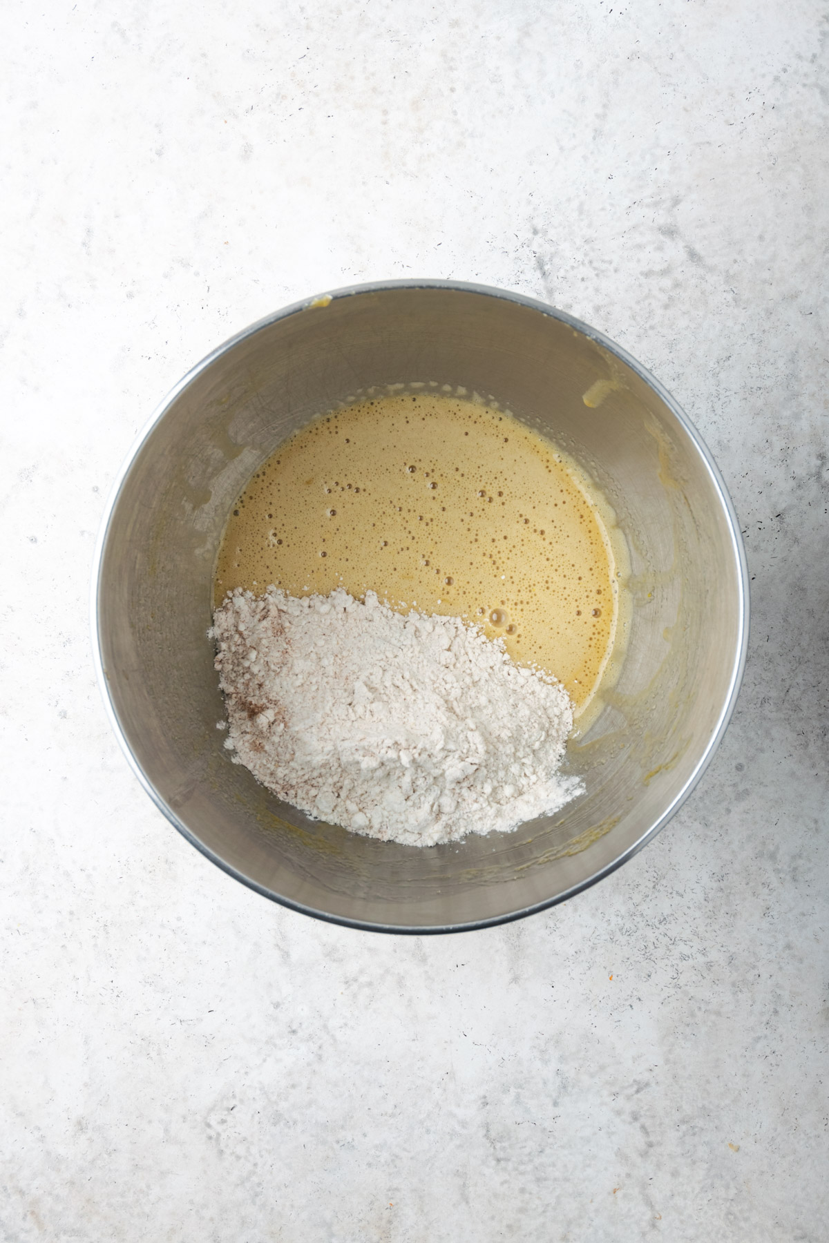 Partially mixed batter in a metal bowl.