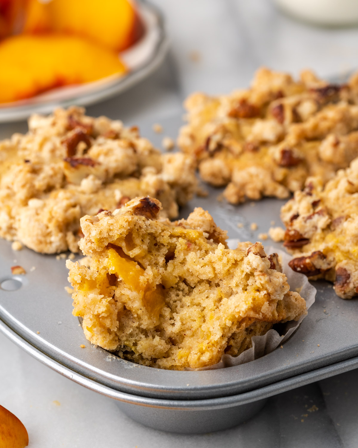 A gluten free peach muffin with a bite taken out.