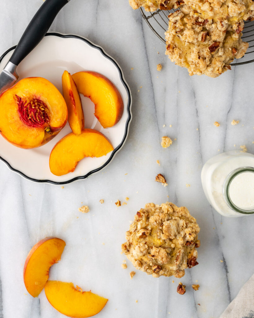 Peach muffins and milk on a marble counter.