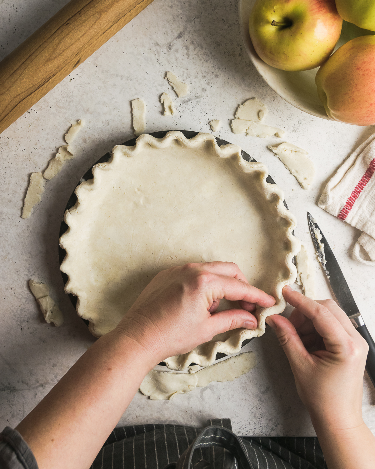 Pie crust being crimped at edges.