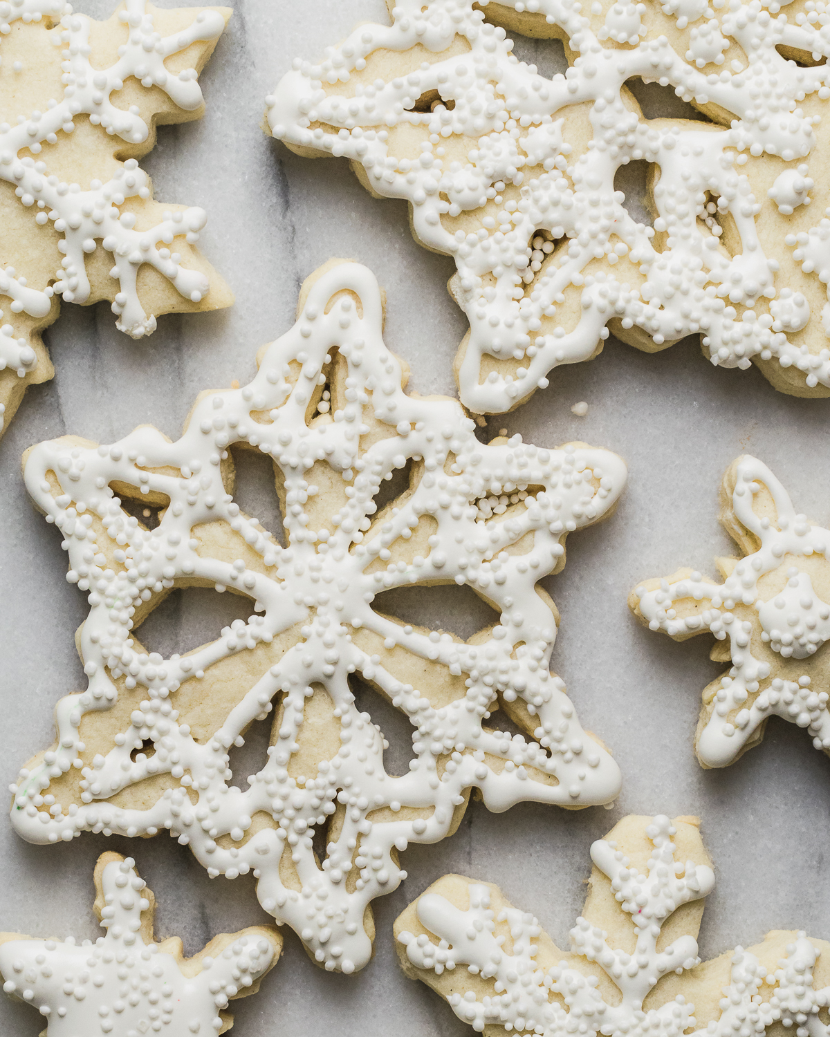 Snowflake sugar cookies decorated with white royal icing and sugar pearls.