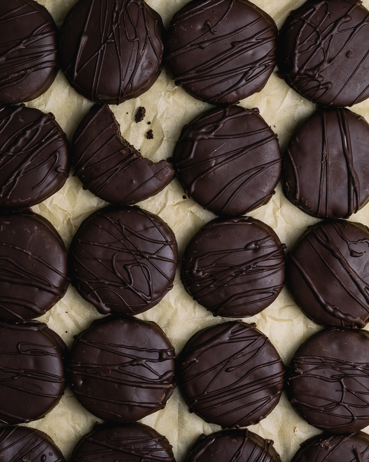 Rows of gluten free thin mints with a bite taken out of one cookie.