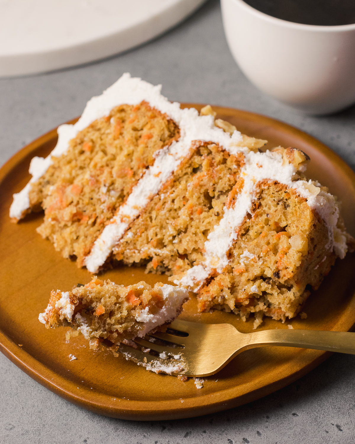Slice of carrot cake on a wooden plate.