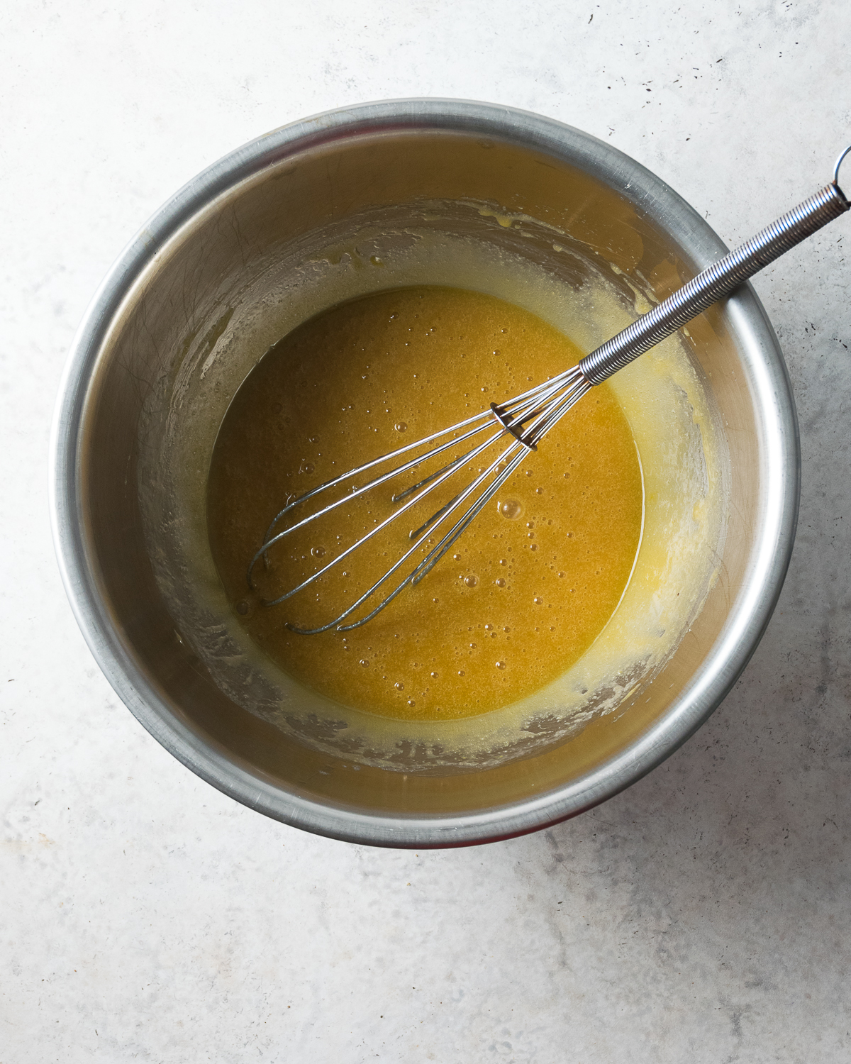 Melted butter and sugar whisked in a metal bowl.