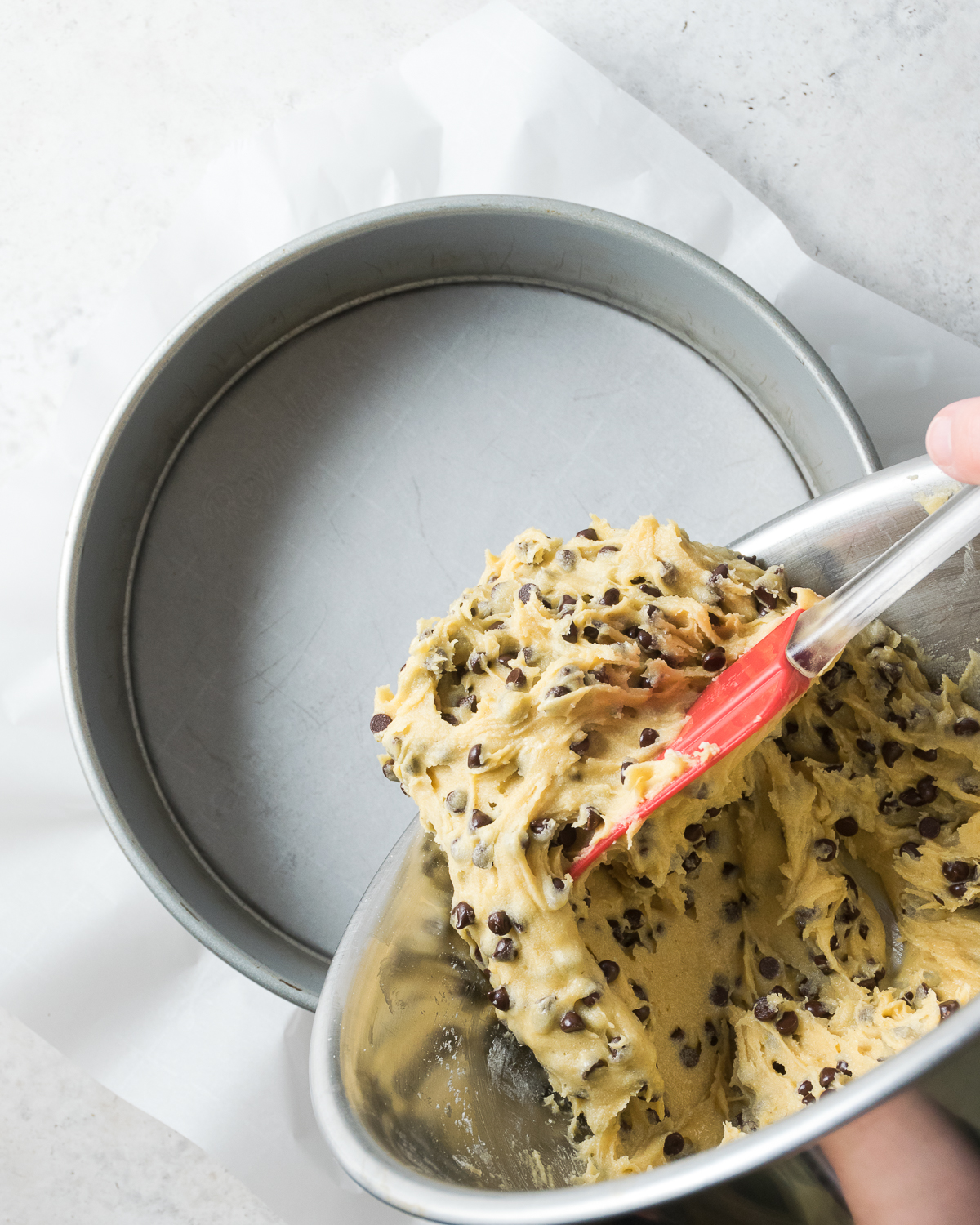 Cookie batter being poured into a springform pan.