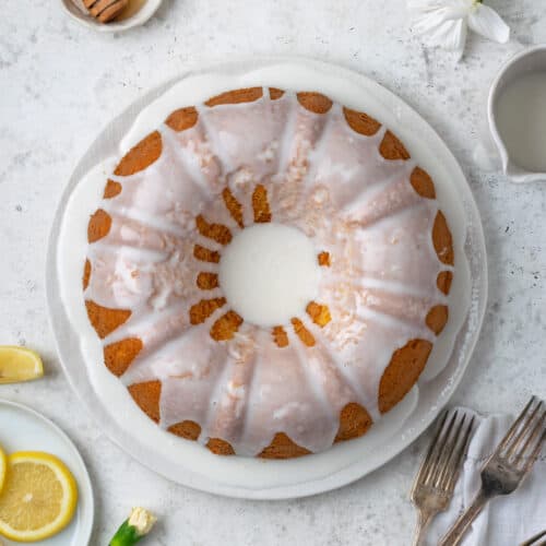 A lemon bundt cake topped with white icing served on a white plate.