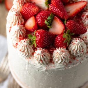 Gluten free strawberry cake topped with cream cheese frosting and fresh strawberries.