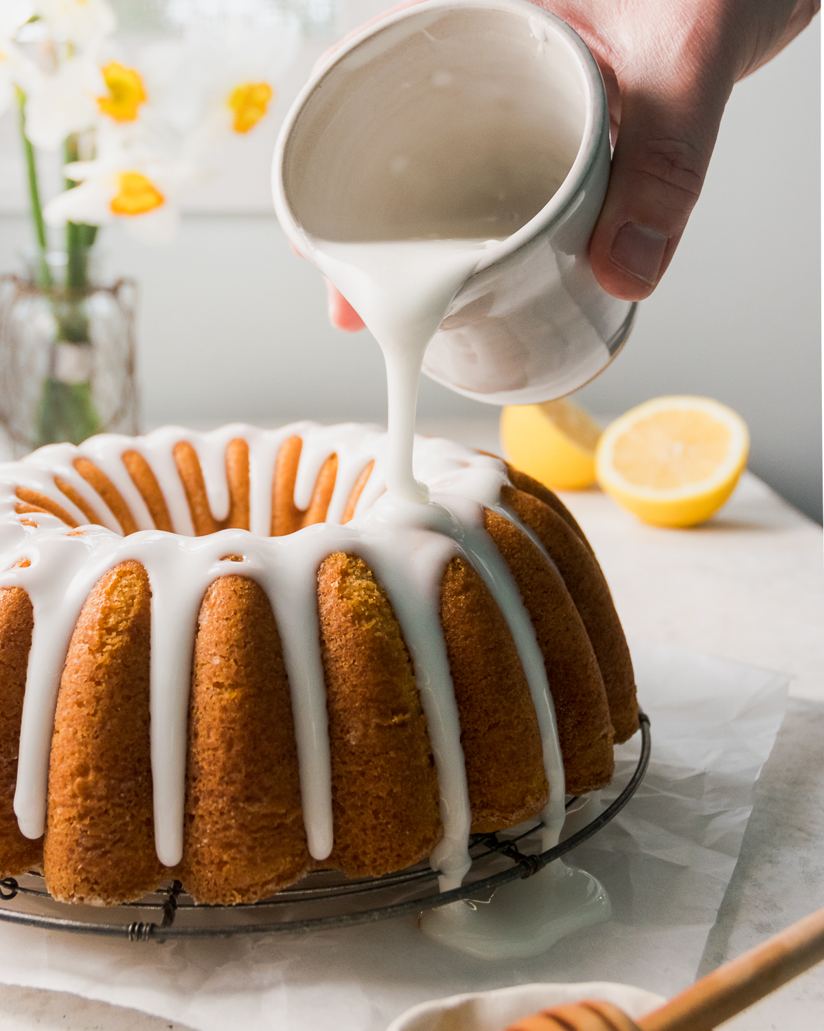Glaze being poured over lemon bundt cake.