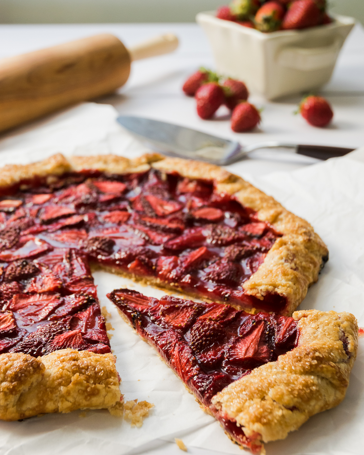 Sliced strawberry galette on a white table.