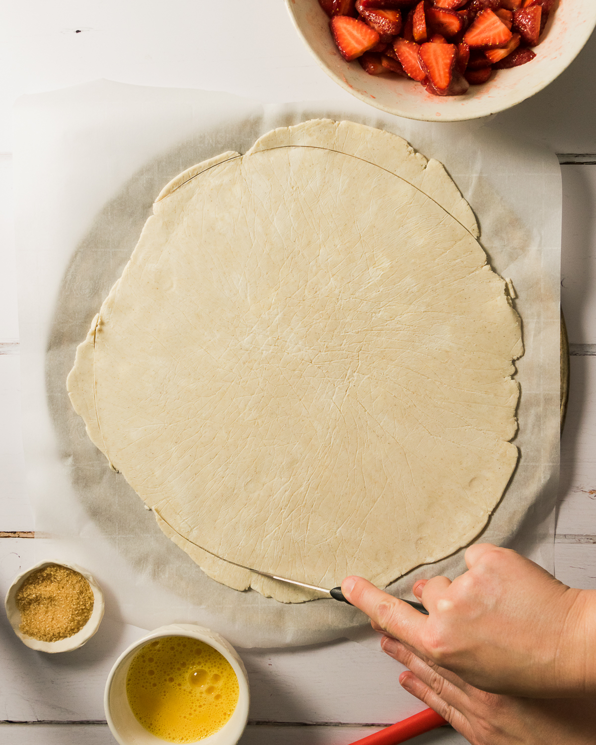 Gluten free pie dough rolled into a large circle and laid on a piece of parchment paper.