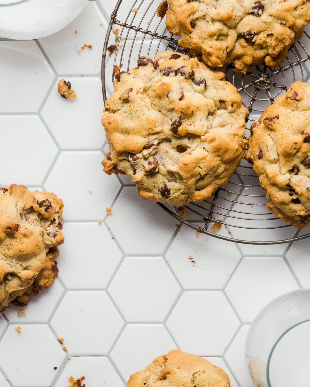 Gluten free levain cookies on a baking rack on a white table.