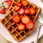 Two strawberry waffles topped with syrup and slices of fresh strawberries.