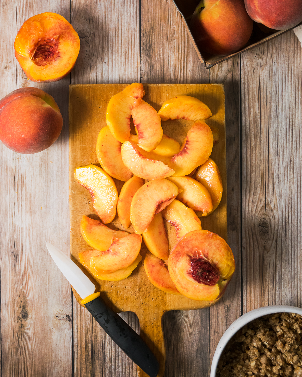 Sliced peaches on a wooden cutting board.