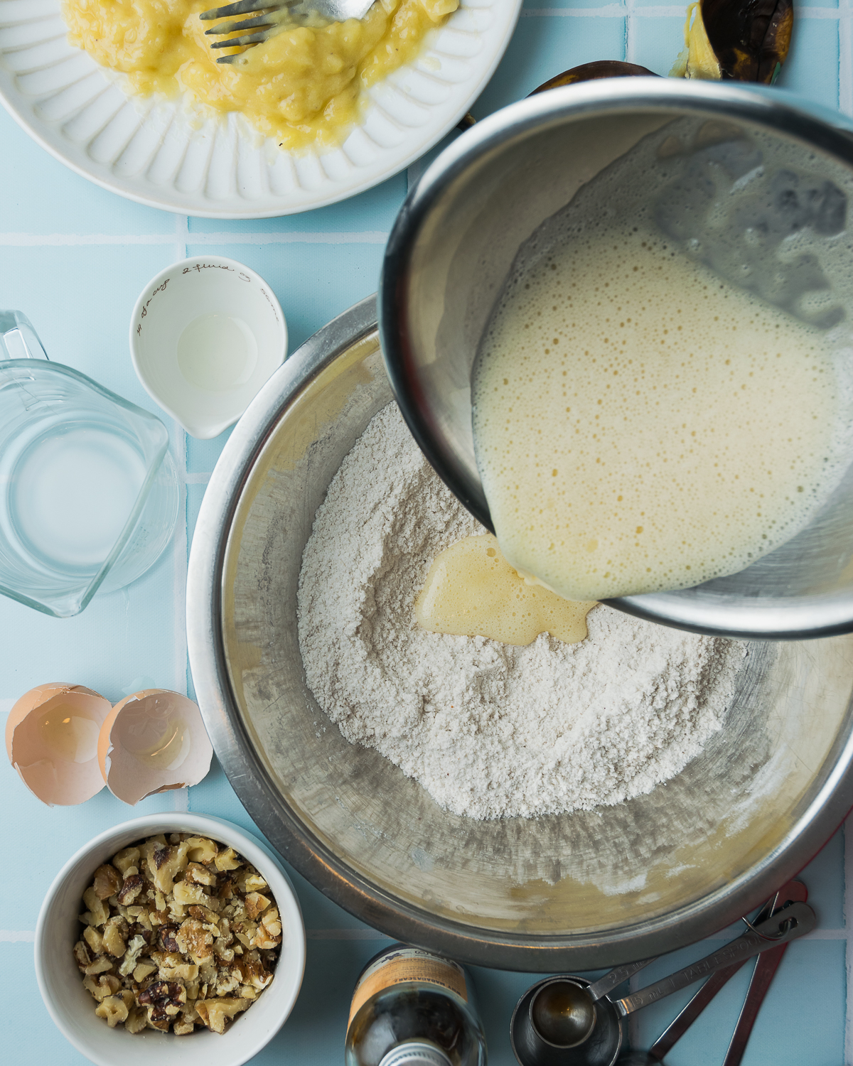 Wet ingredients being poured into a bowl of dry ingredients.