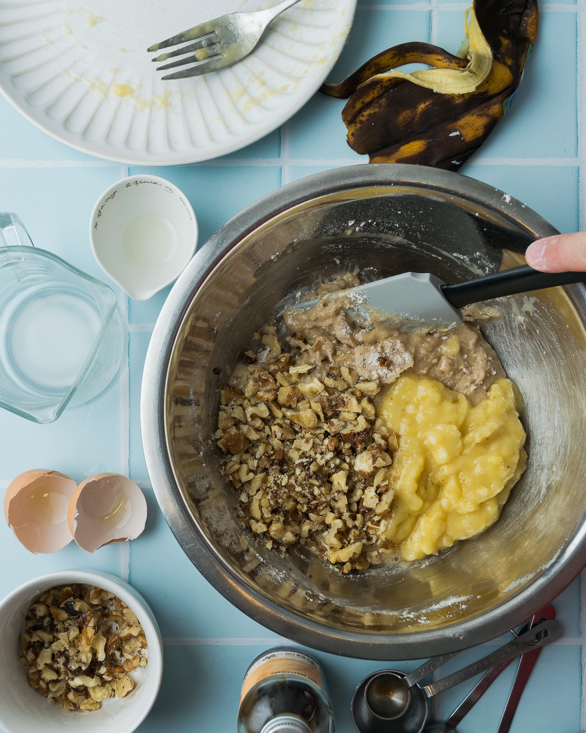 Mashed banana and walnuts being added to muffin batter.