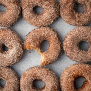 A table of gluten free apple cider donuts with one partially eaten.