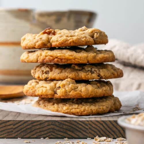 A stack of five gluten free oatmeal raisin cookies sitting on a wooden board.