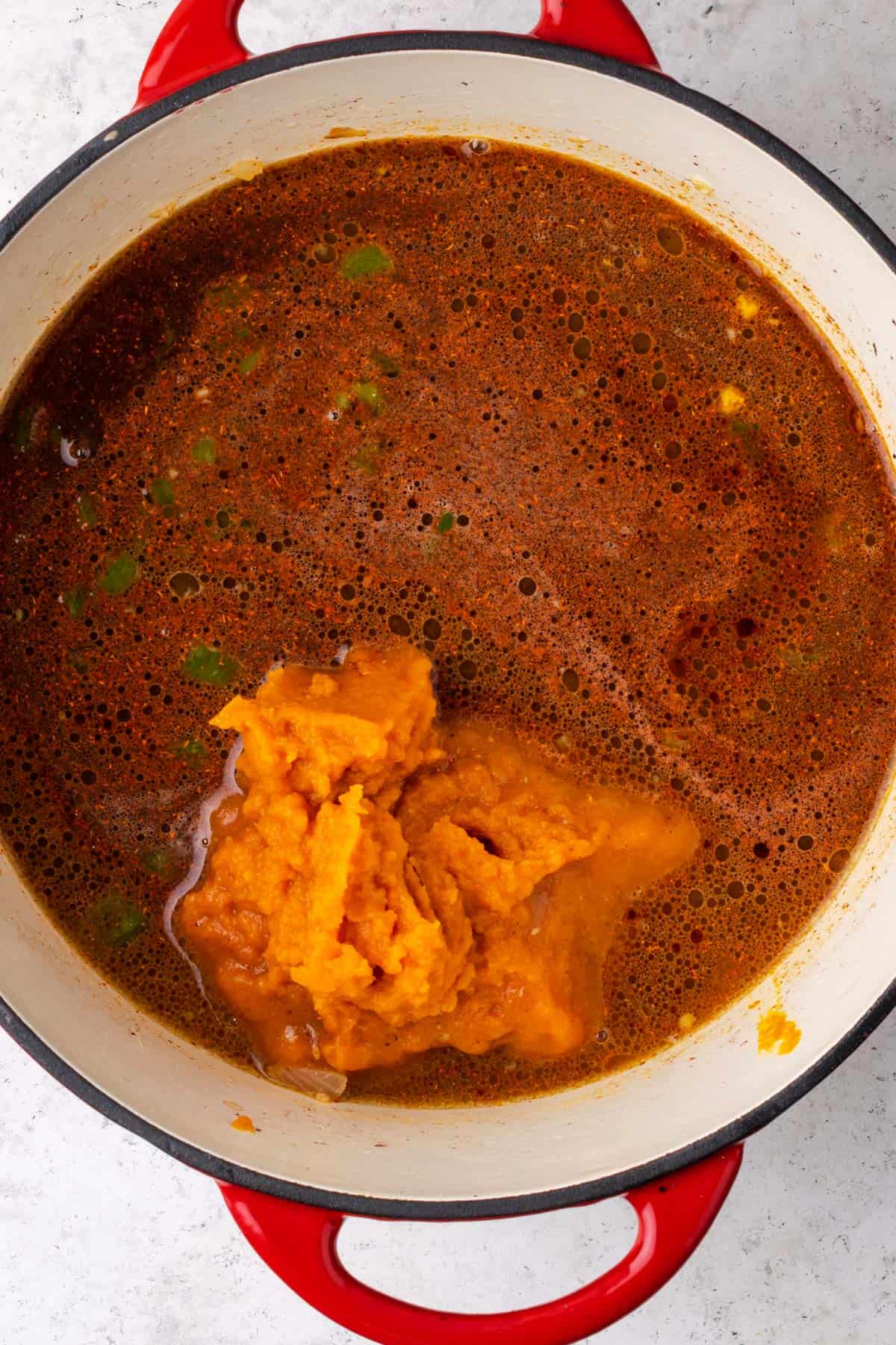 Beef broth, pumpkin and spices being added to the soup pot.