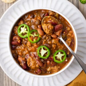 A bowl of pumpkin chili topped with sliced jalapenos.