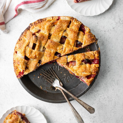 A sliced gluten free apple cranberry pie on a white table.