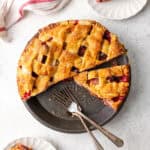 A sliced apple cranberry pie sitting in a pie plate on a countertop.
