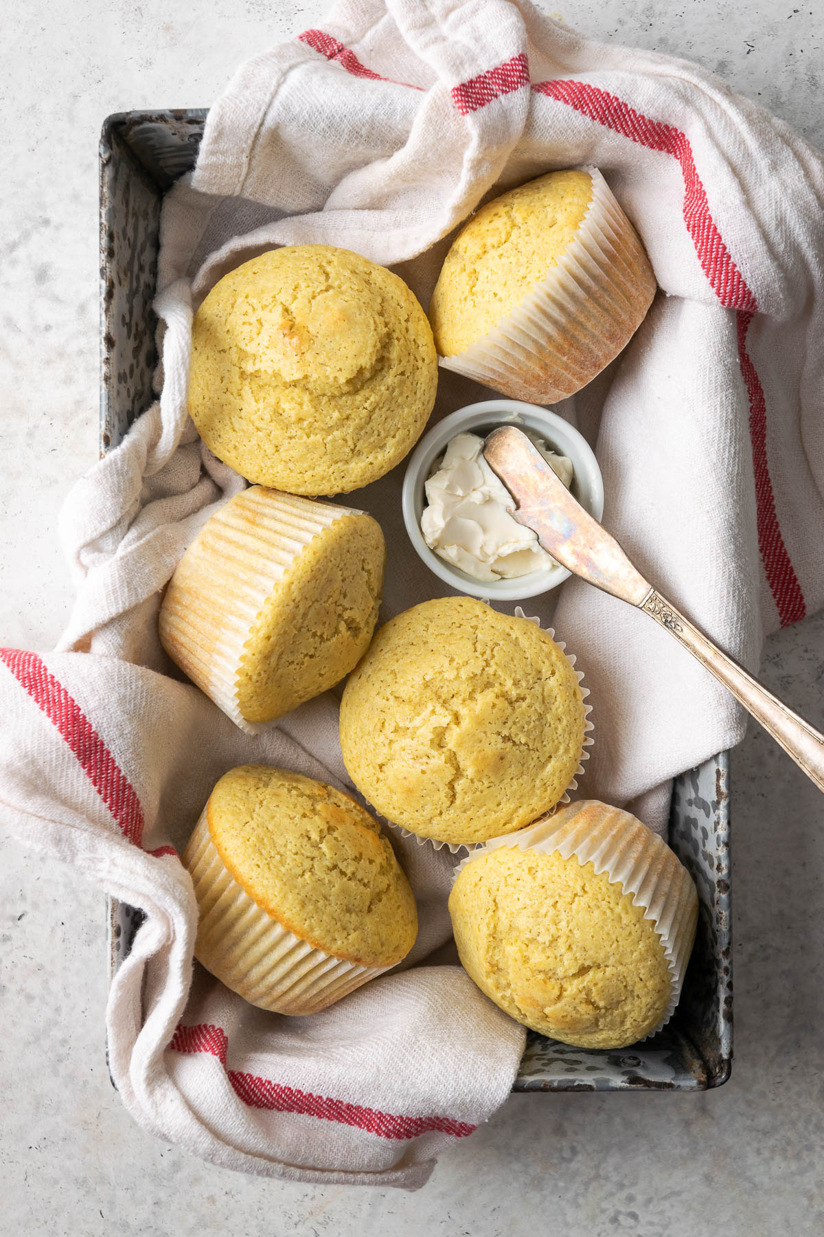 A basket of gluten free corn muffins on a white table.