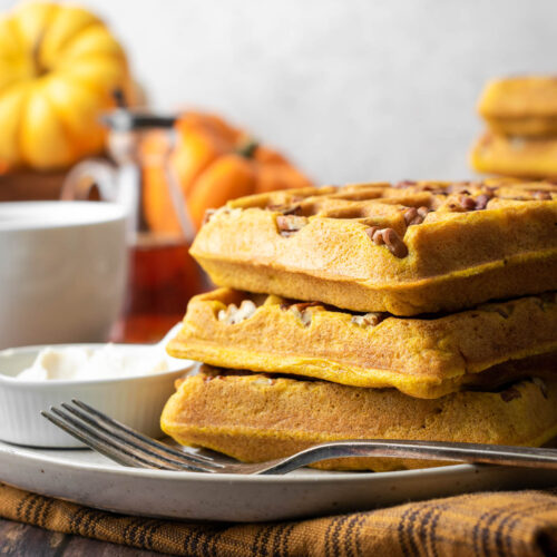 A stack of three gluten free pumpkin waffles on a serving plate.