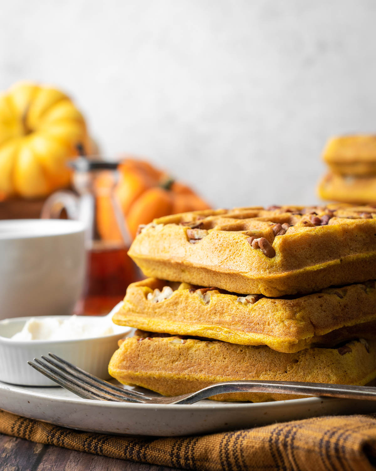 A stack of pumpkin waffles on a plate.